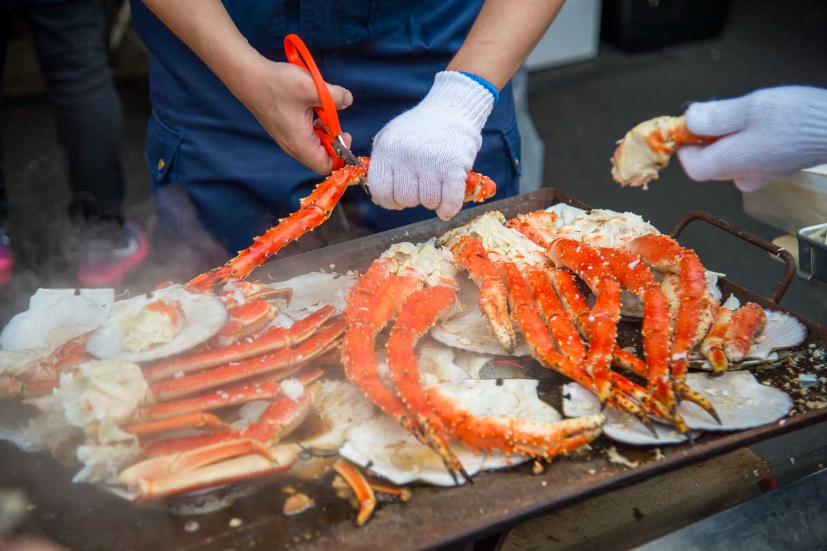 A person cooks crab legs at Tsukiji Market on a tour in Tokyo Japan
