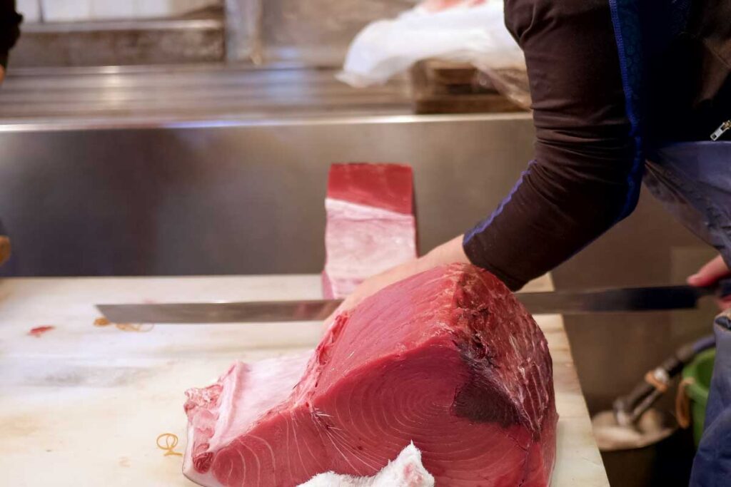 A person prepapres fish on a Tsukiji Market on a tour in Tokyo Japan