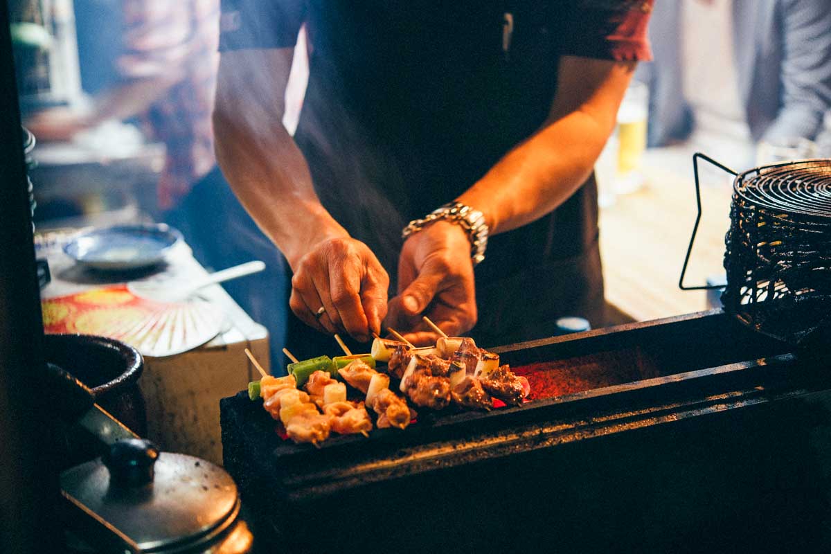 A man cooking street food in omoide yokocho Tokyo Japan