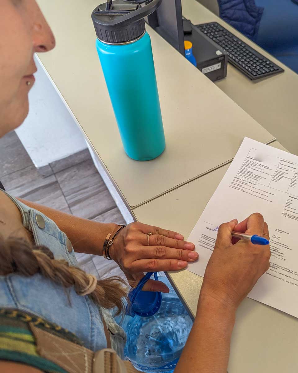 Bailey signs the rental paperwork renting a car in Japan